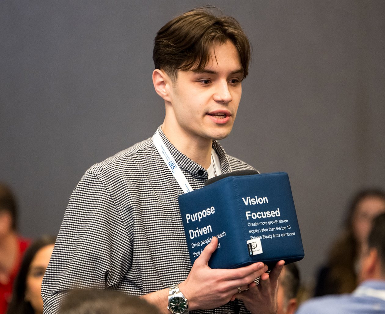 Davyd speaking at an SBI session, holding a throwable microphone printed with the company’s values